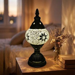 Lampe de table mosaïque style Tiffany allumée sur une table de chevet en bois dans une chambre chaleureuse