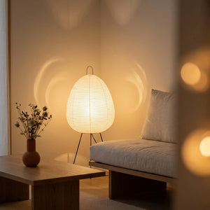 Lampe style Noguchi en papier de riz allumée dans un salon au coucher du soleil lumière chaude