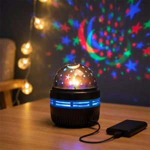 Lampe projecteur galaxie posée sur un bureau en bois avec guirlande lumineuse en fond