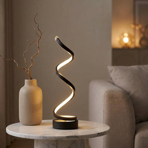Lampe spirale LED allumée sur une table basse en marbre dans un salon