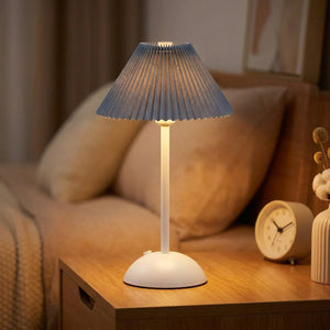 Lampe de table sans fil avec abat-jour plissé bleu allumée sur une table de nuit