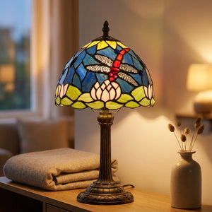 Lampe vitrail Tiffany libellule posée sur une console salon avec plaid et vase