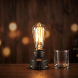 Lampe tuyau industrielle allumée sur un comptoir de bar en bois avec un verre