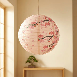 Lanterne japonaise en papier motif fleurs de cerisier rose suspendue dans un intérieur zen