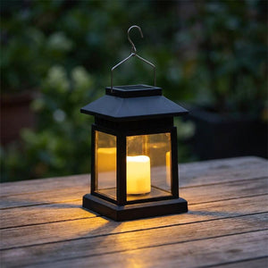Lanterne solaire avec bougie LED allumée sur une table de jardin