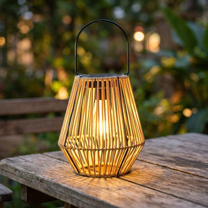 Lanterne solaire géométrique style rotin posée sur une table de jardin en bois au crépuscule