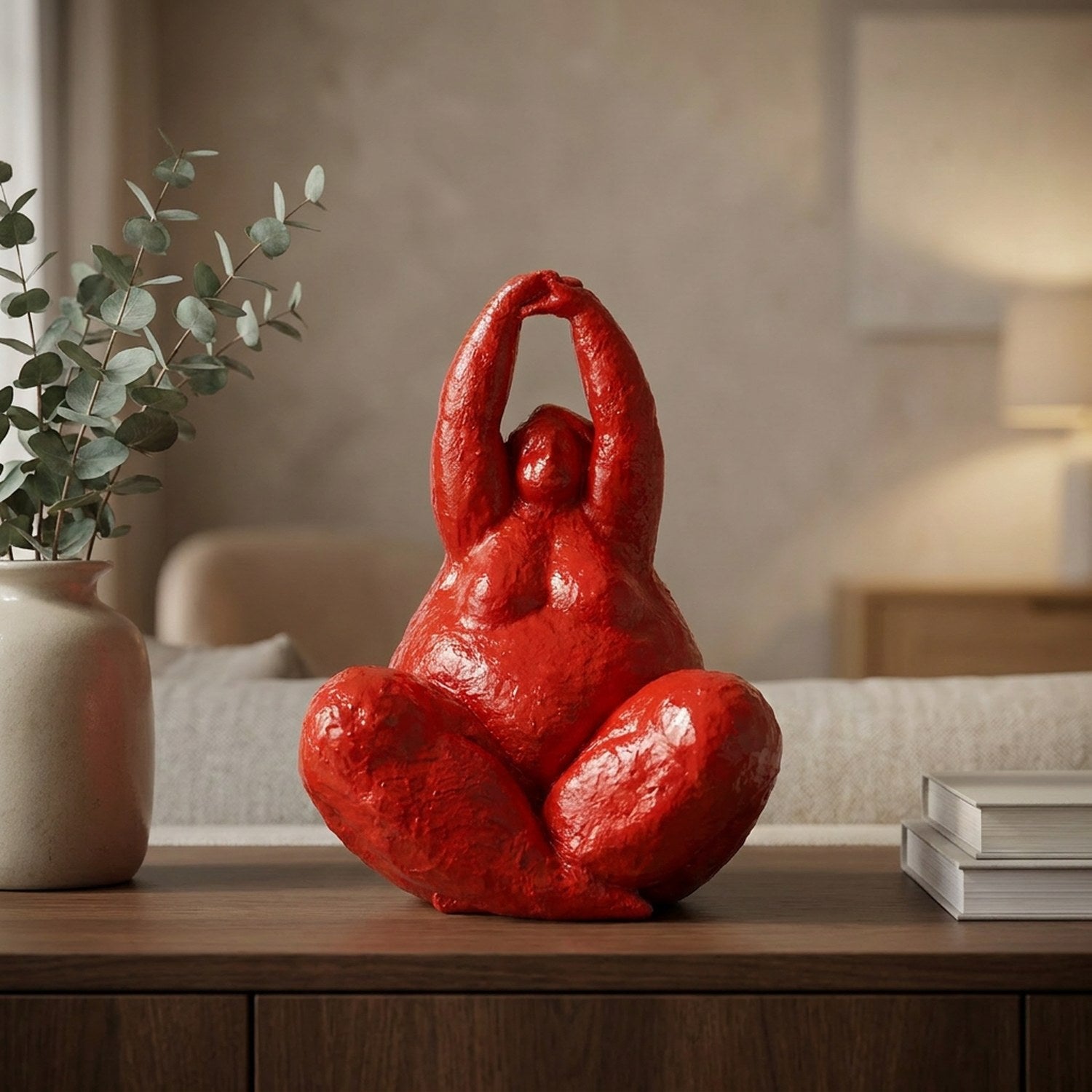 Statue de femme ronde rouge laqué sur un buffet en bois avec vase d'eucalyptus