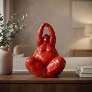 Statue de femme ronde rouge laqué sur un buffet en bois avec vase d'eucalyptus