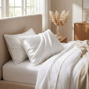 Taies d'oreiller satin blanches installées sur un lit dans une chambre chaleureuse