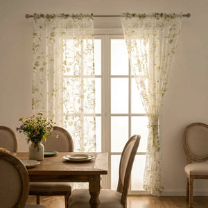 Voilage tulle fleuri devant une porte fenêtre dans une salle à manger champêtre avec table en bois