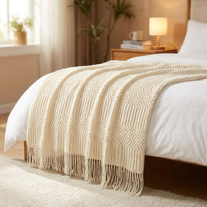 Plaid tricoté crème posé au pied d un lit dans une chambre chaleureuse