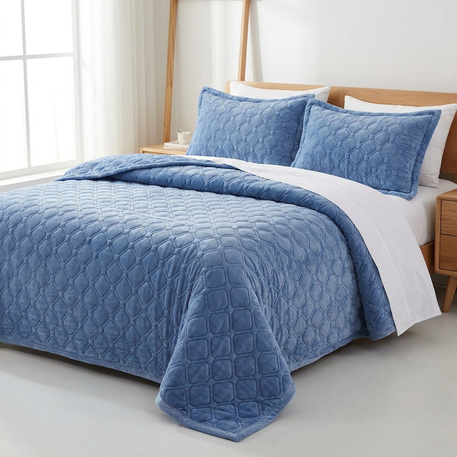 Couvre-lit matelassé bleu replié laissant apparaître le drap blanc dans une chambre lumineuse