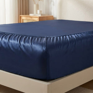 Détail de l'élastique du drap-housse satin bleu marine sur le coin du matelas