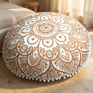 Coussin de sol mandala doré posé au pied d'un lit dans une chambre bohème