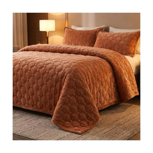 Couvre-lit matelassé terracotta au pied du lit avec lampe de chevet allumée