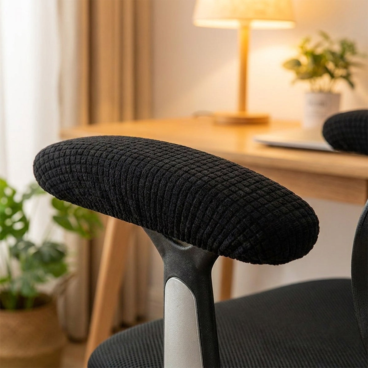 Gros plan sur une housse d'accoudoir noire en tissu texture epousant l'accoudoir d'une chaise de bureau