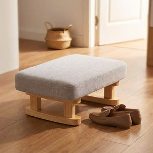 Tabouret rembourré gris utilisé dans une entrée avec des chaussures
