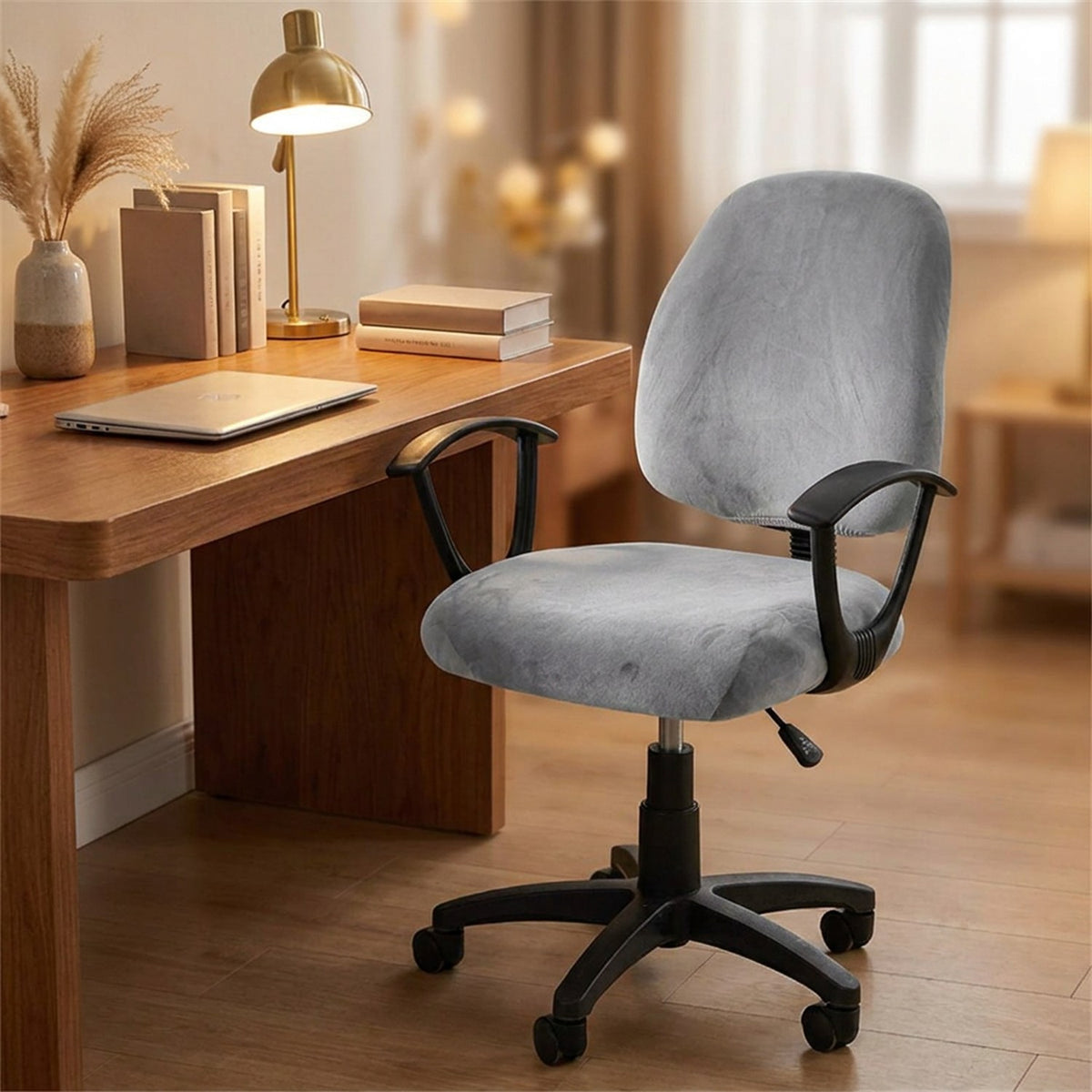 Housse de chaise de bureau grise en velours installée sur un fauteuil devant un bureau en bois avec une lampe