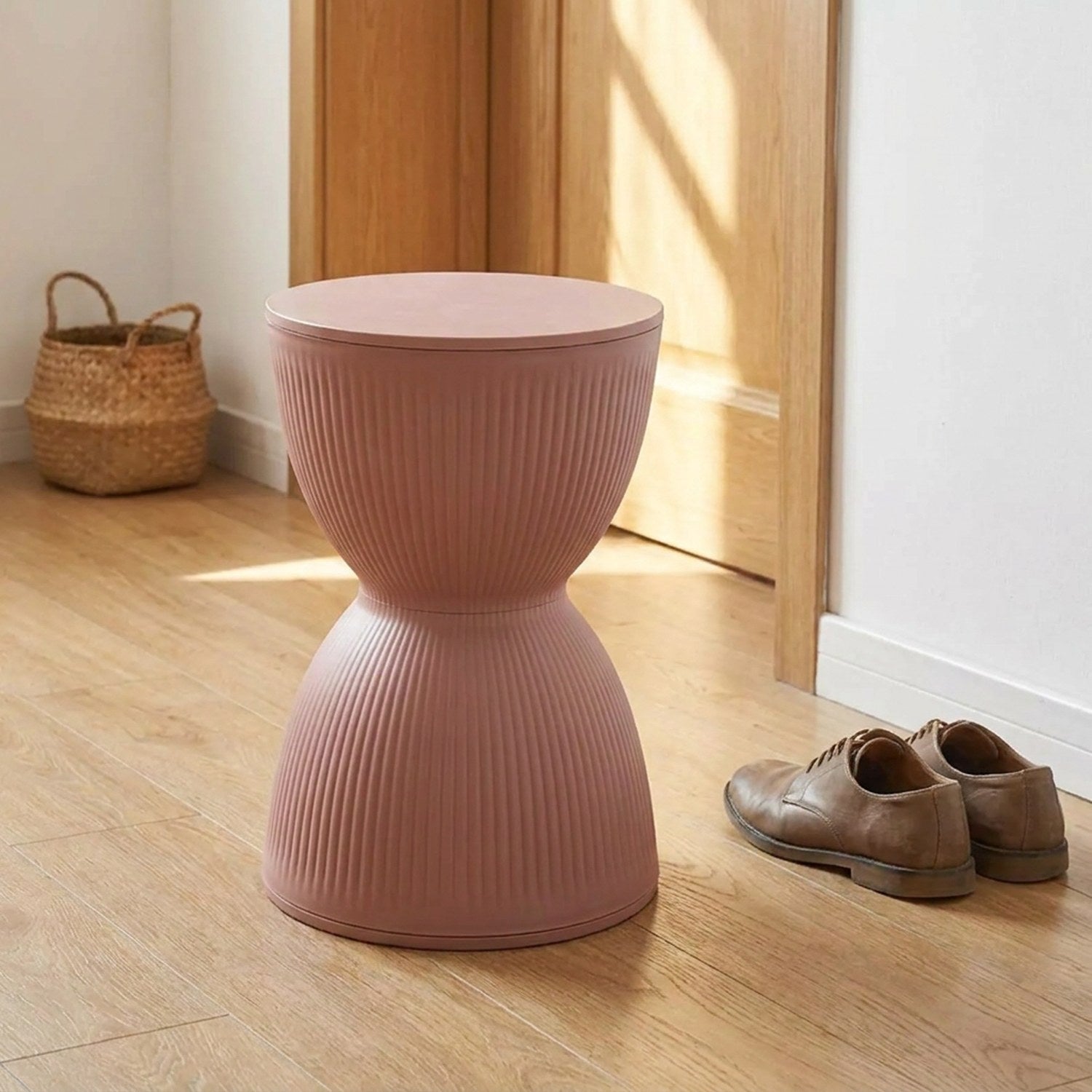 Tabouret rond nordique rose utilisé dans une entrée avec des chaussures