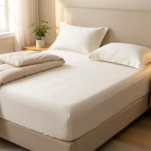 Drap-housse blanc fait sur un grand lit dans une chambre lumineuse avec une plante verte