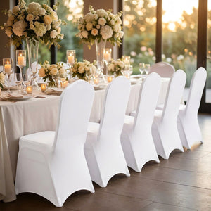 Rangée de chaises habillées de housses blanches le long d'une longue table de réception fleurie
