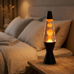 Lampe à lave allumée sur une table de chevet dans une chambre chaleureuse