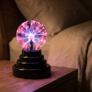 Lampe boule de plasma allumée sur une table de chevet dans une chambre cosy