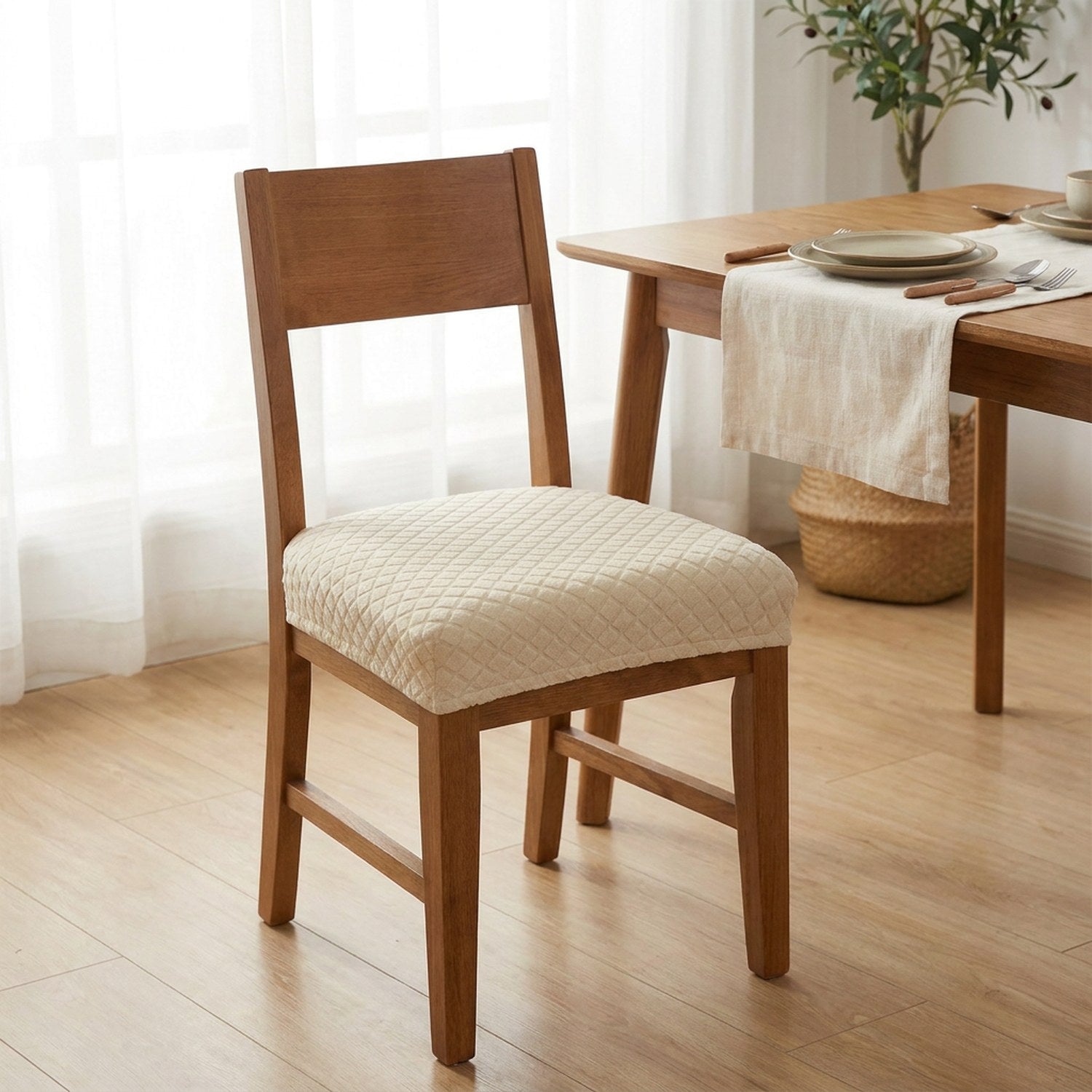 Chaise en bois habillée d'une housse de siège imperméable beige devant une table dressée