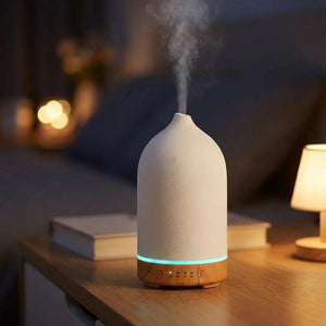 Diffuseur en céramique allumé en lumière bleue sur une table de nuit le soir