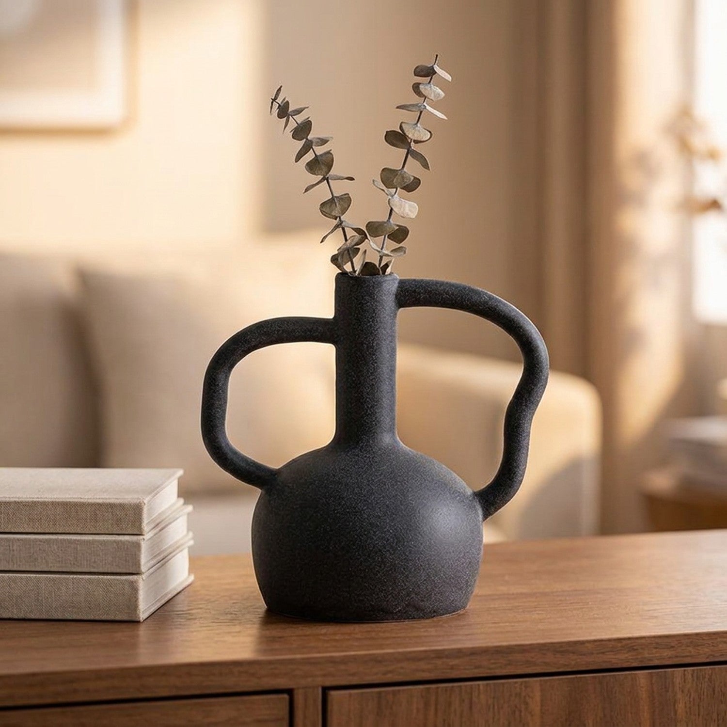 Vase en céramique noir avec eucalyptus séché posé sur un buffet en bois