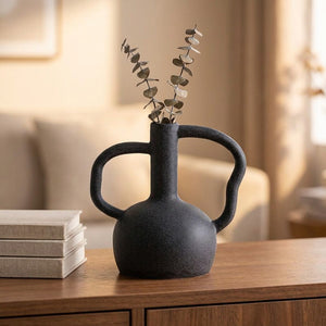 Vase en céramique noir avec eucalyptus séché posé sur un buffet en bois