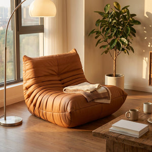 Pouf géant canapé de sol cognac dans un coin lecture chaleureux avec lampadaire et plante verte