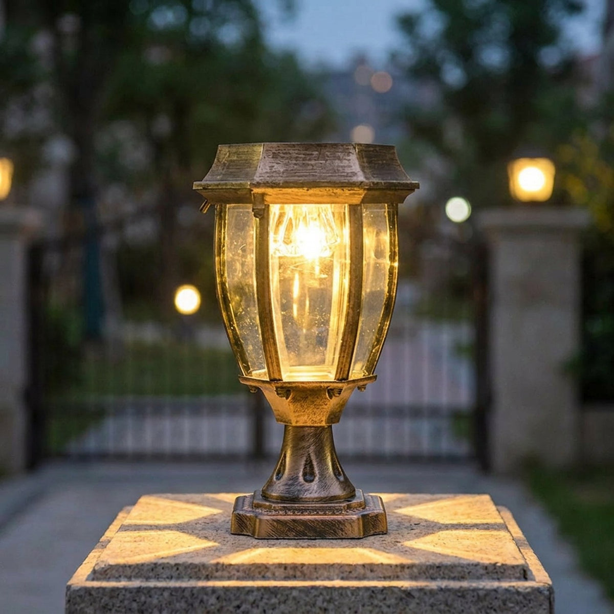 Lanterne solaire bronze posée sur un pilier de portail illuminant l'entrée à la tombée du jour