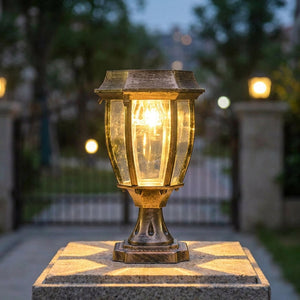 Lanterne solaire bronze posée sur un pilier de portail illuminant l'entrée à la tombée du jour