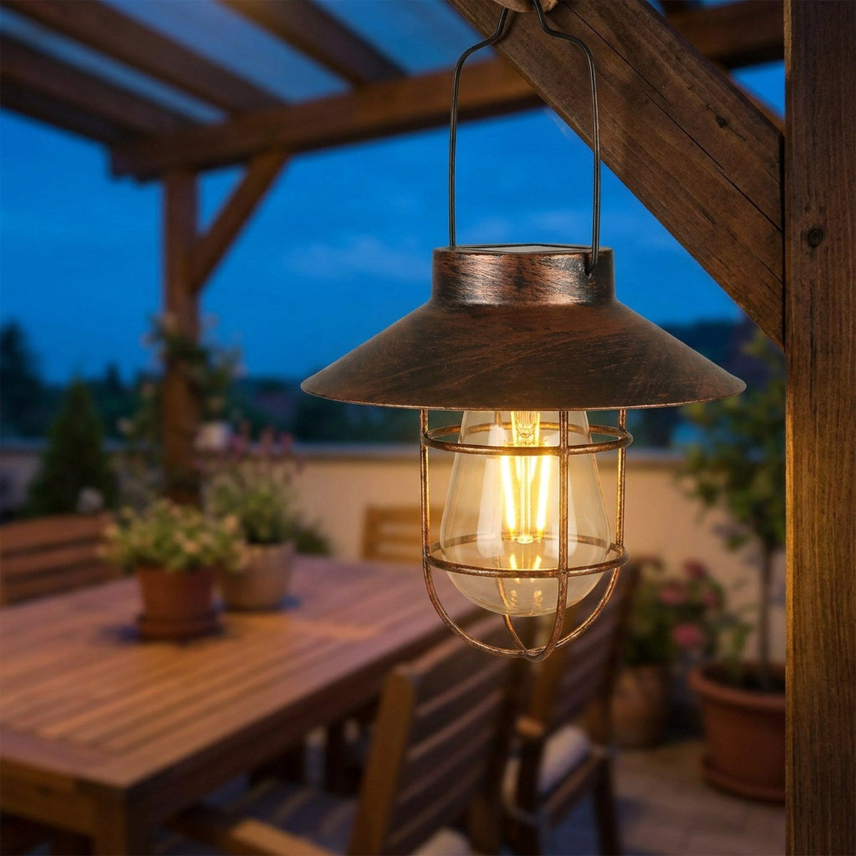 Lanterne solaire bronze allumée suspendue à une pergola sur une terrasse en soirée