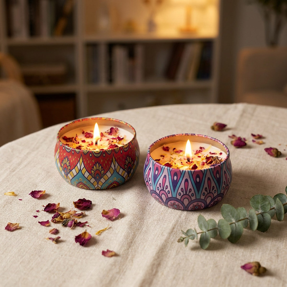 Deux bougies parfumées bohème allumées sur une nappe en lin avec des pétales séchés