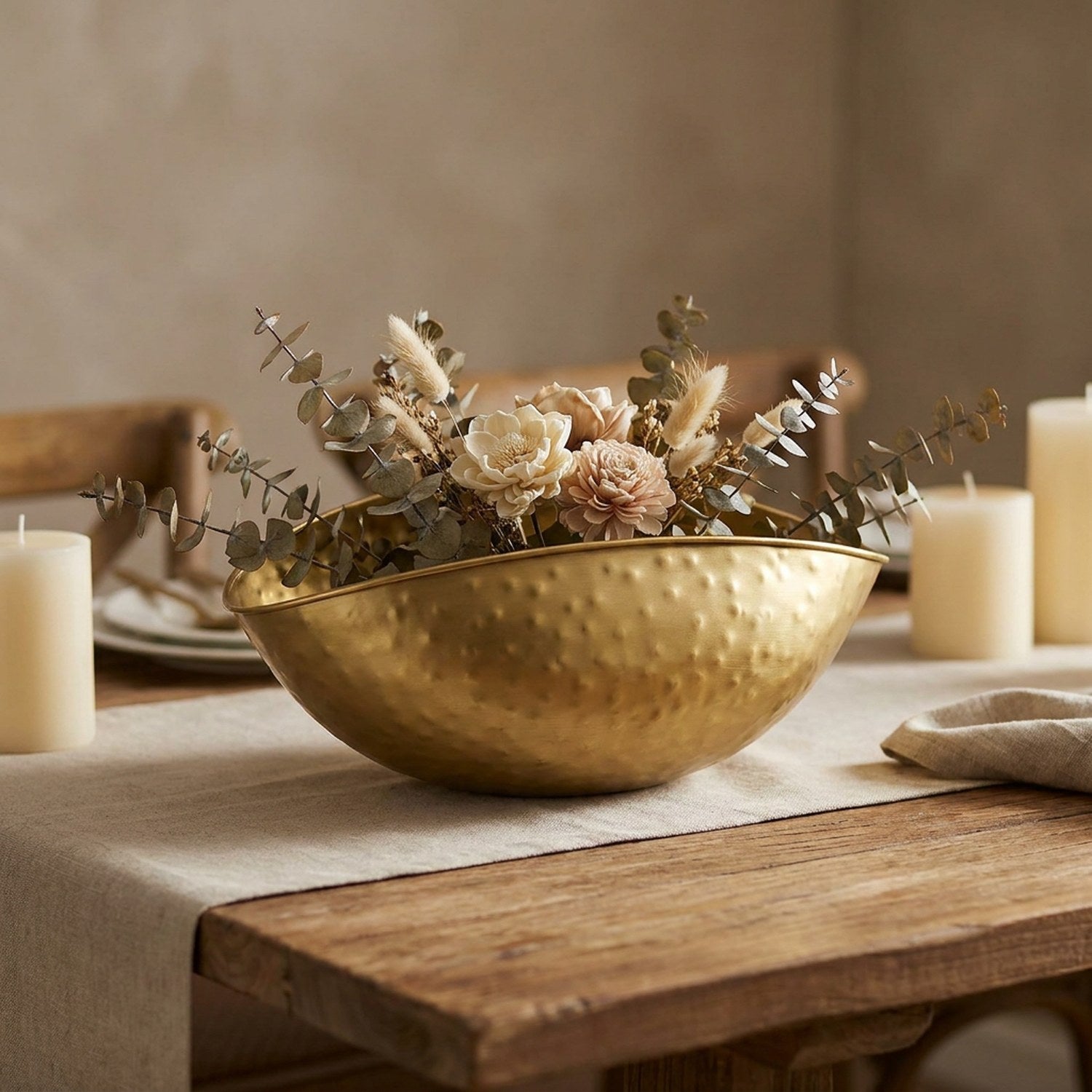 Coupe dorée en centre de table sur une table dressée avec fleurs séchées et bougies