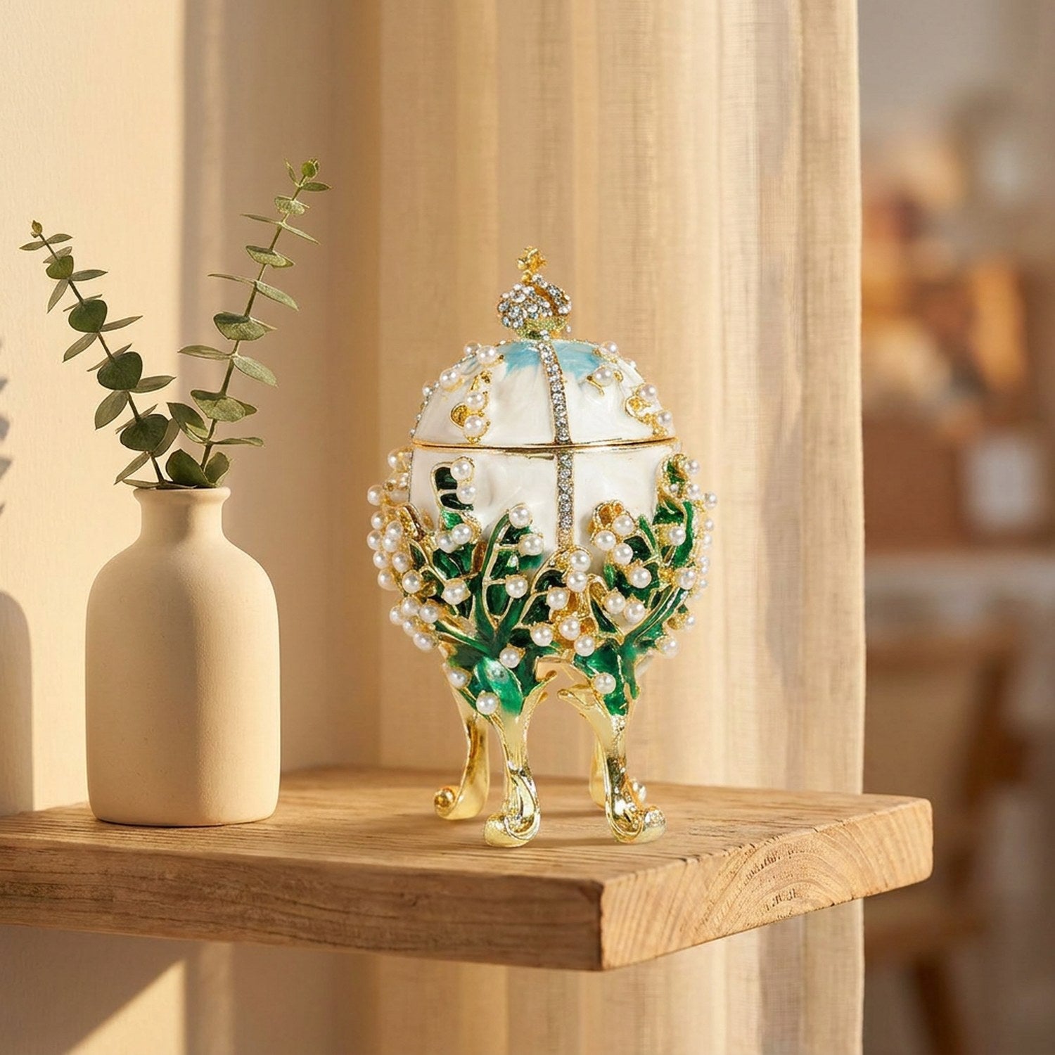 Boîte à bijoux œuf émaillé blanc sur une étagère en bois avec brin d'eucalyptus