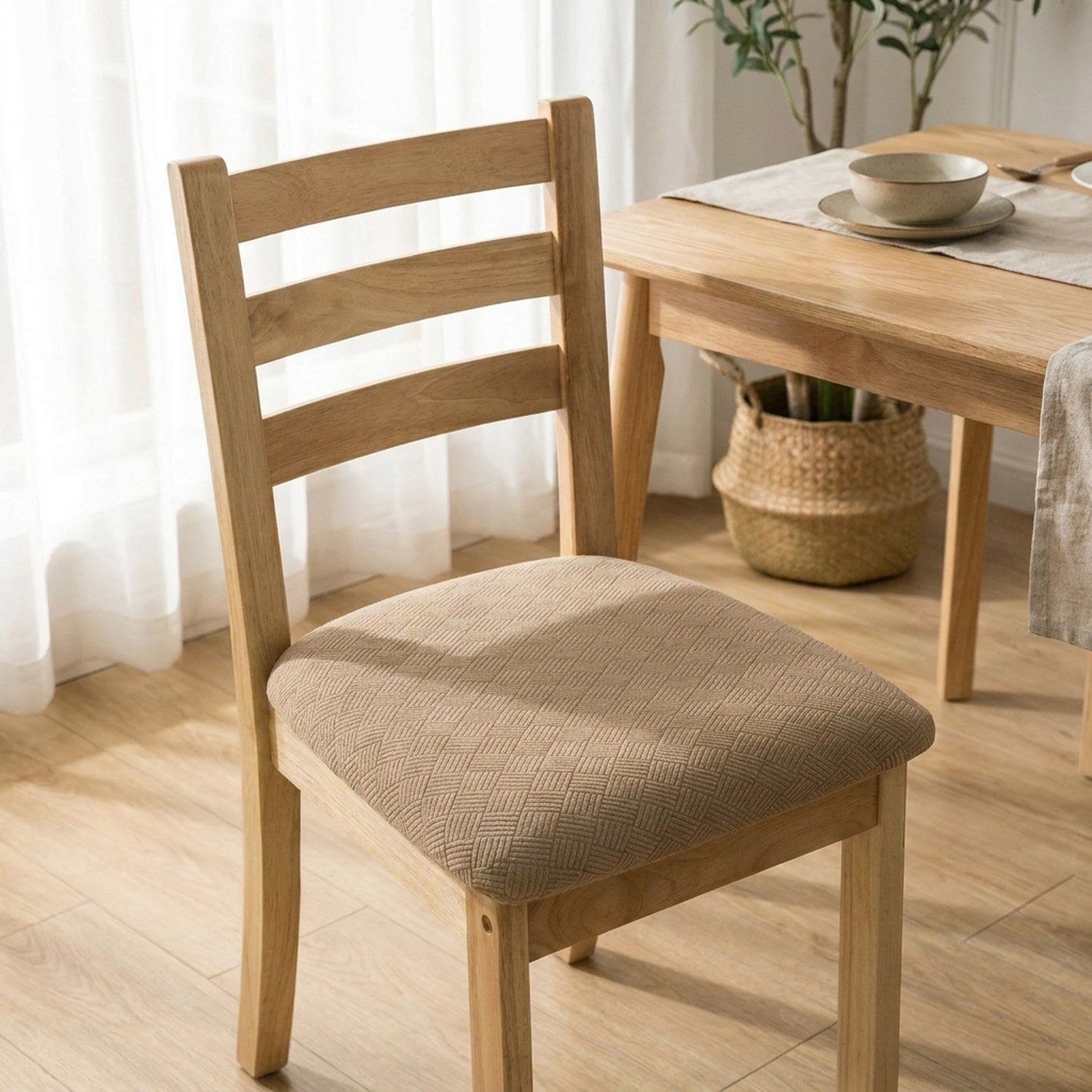 Chaise en bois habillée d'une housse de siège beige devant une table de salle à manger dressée