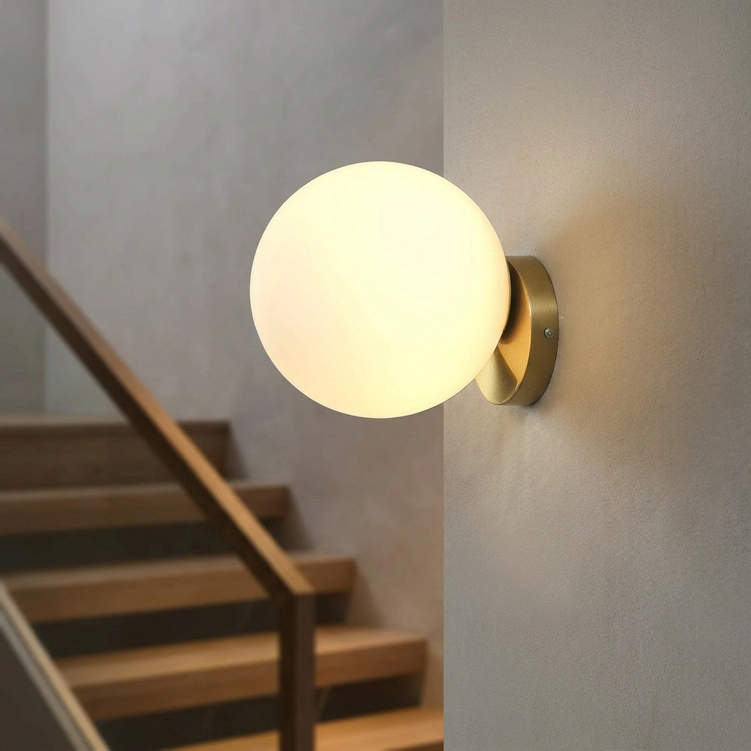 Applique murale boule de verre dorée éclairant un escalier en bois le soir