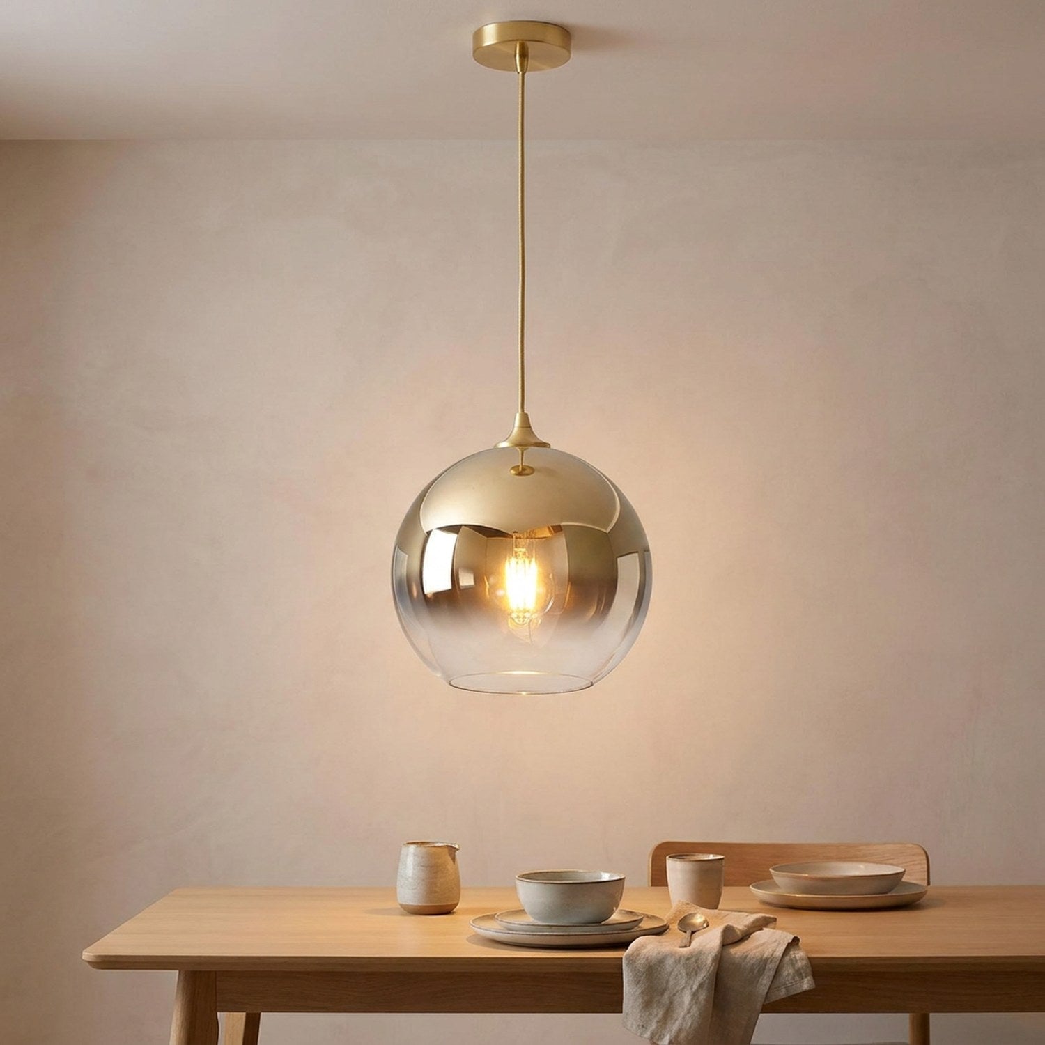 Suspension boule de verre dorée au-dessus d'une table de salle à manger scandinave