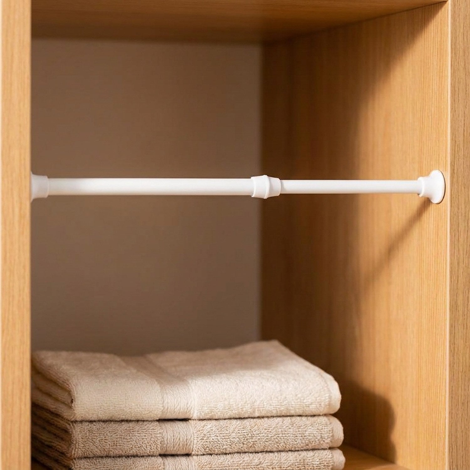 Tringle blanche fine utilisée comme séparateur d'étagère dans un placard en bois