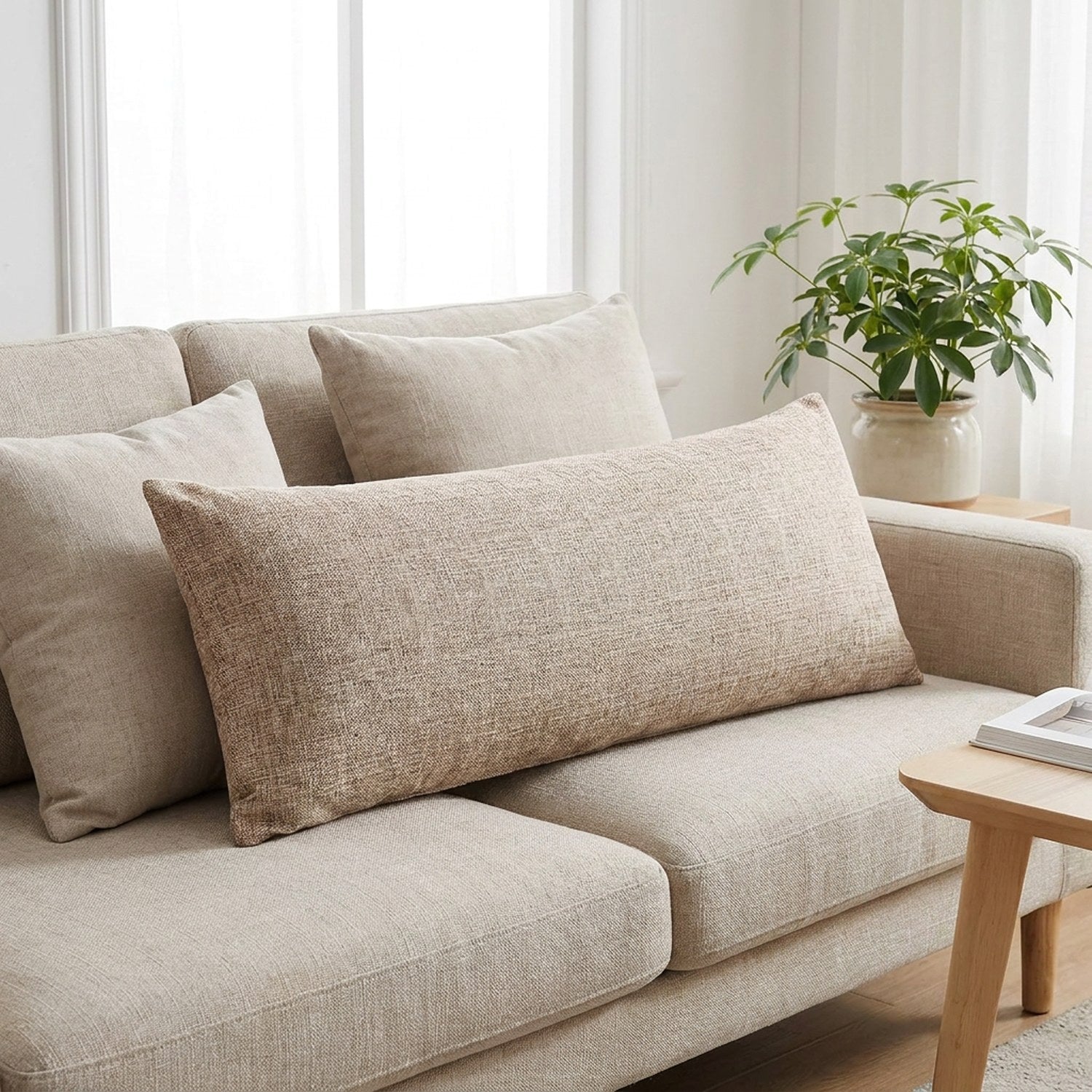 Housse de coussin longue beige sur un canapé en lin avec plante