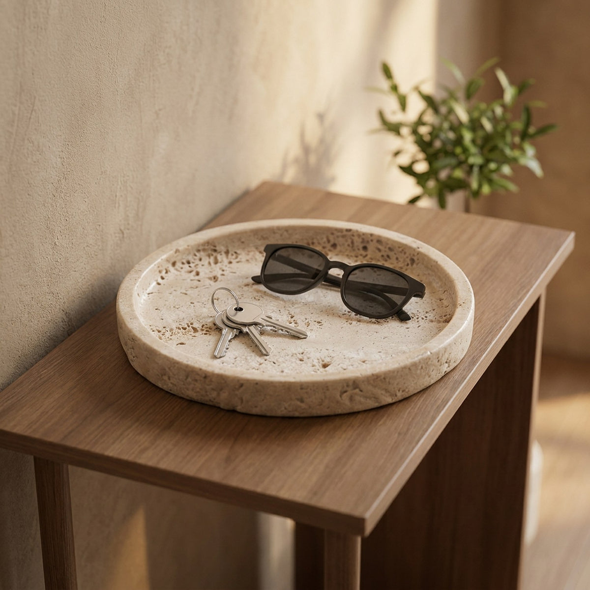 Plateau en pierre beige sur une console d'entrée avec clés et lunettes