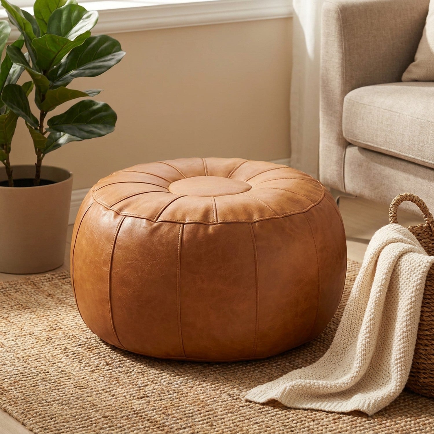 Pouf de rangement caramel dans un coin salon avec plante et plaid