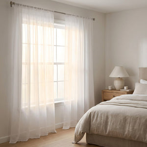 Voilage blanc en voile tamisant devant une grande fenêtre dans une chambre lumineuse