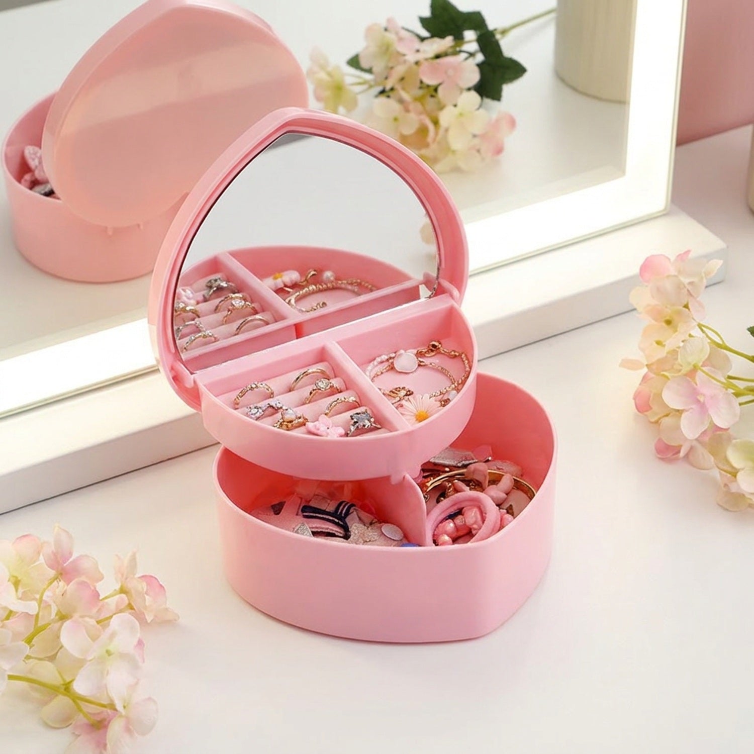 Boîte à bijoux rose ouverte avec bracelets et bagues rangés