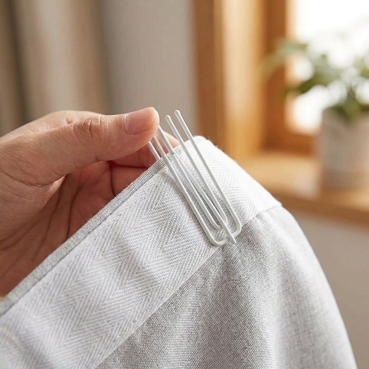 Insertion d'un crochet de rideau blanc dans le ruban fronceur en gros plan