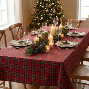 Table de Noël dressée avec une nappe à carreaux tartan rouge et un sapin illuminé