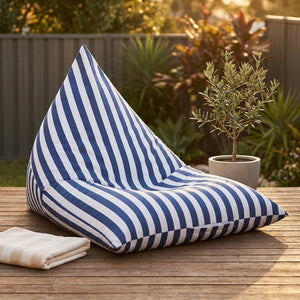 Pouf géant extérieur rayé bleu marine sur une terrasse en bois au coucher du soleil